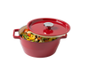 Red enameled cast iron Dutch oven with a lid filled with vegetables on a white background