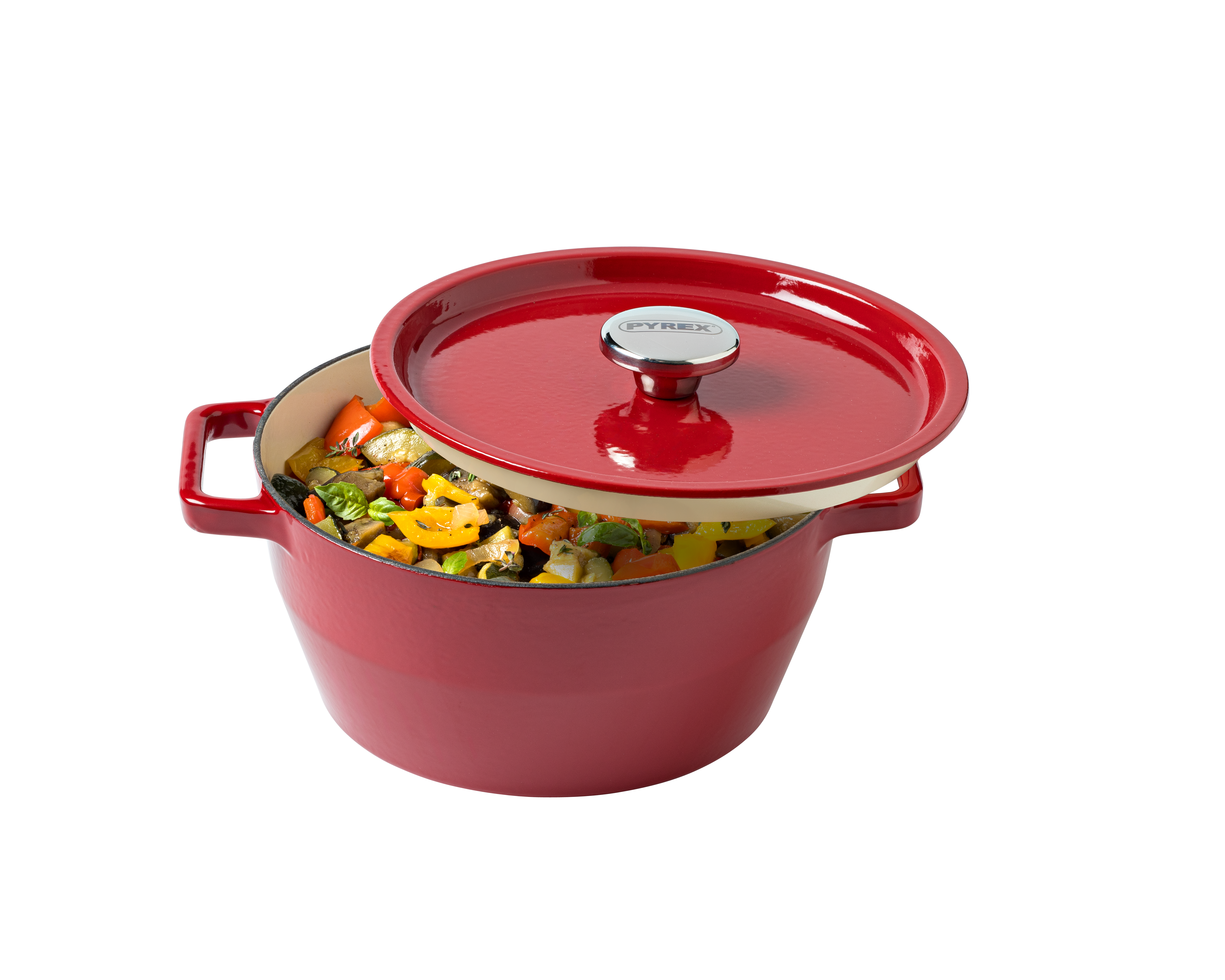 Red enameled cast iron Dutch oven with a lid filled with vegetables on a white background